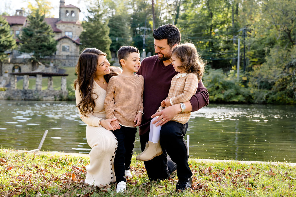 A family laughing beside a pond in a park