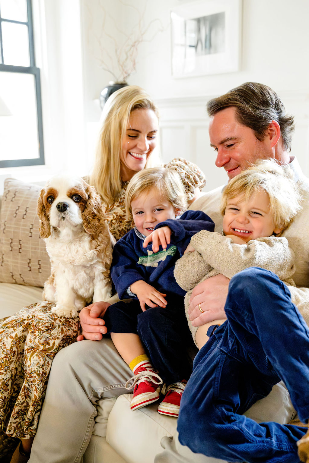 A family laughing together on the sofa with their dog