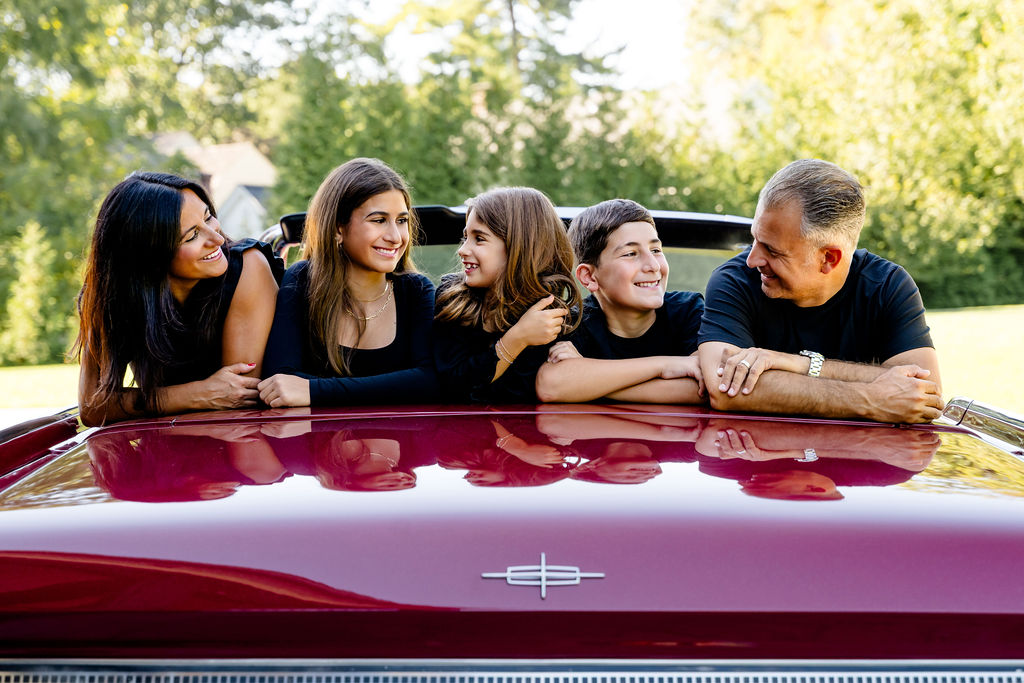 A family leaning over a vintage red car