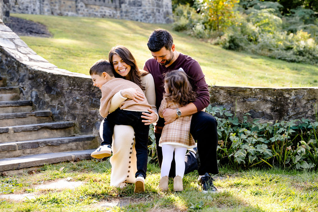 A family of four sitting together on stone steps in a park