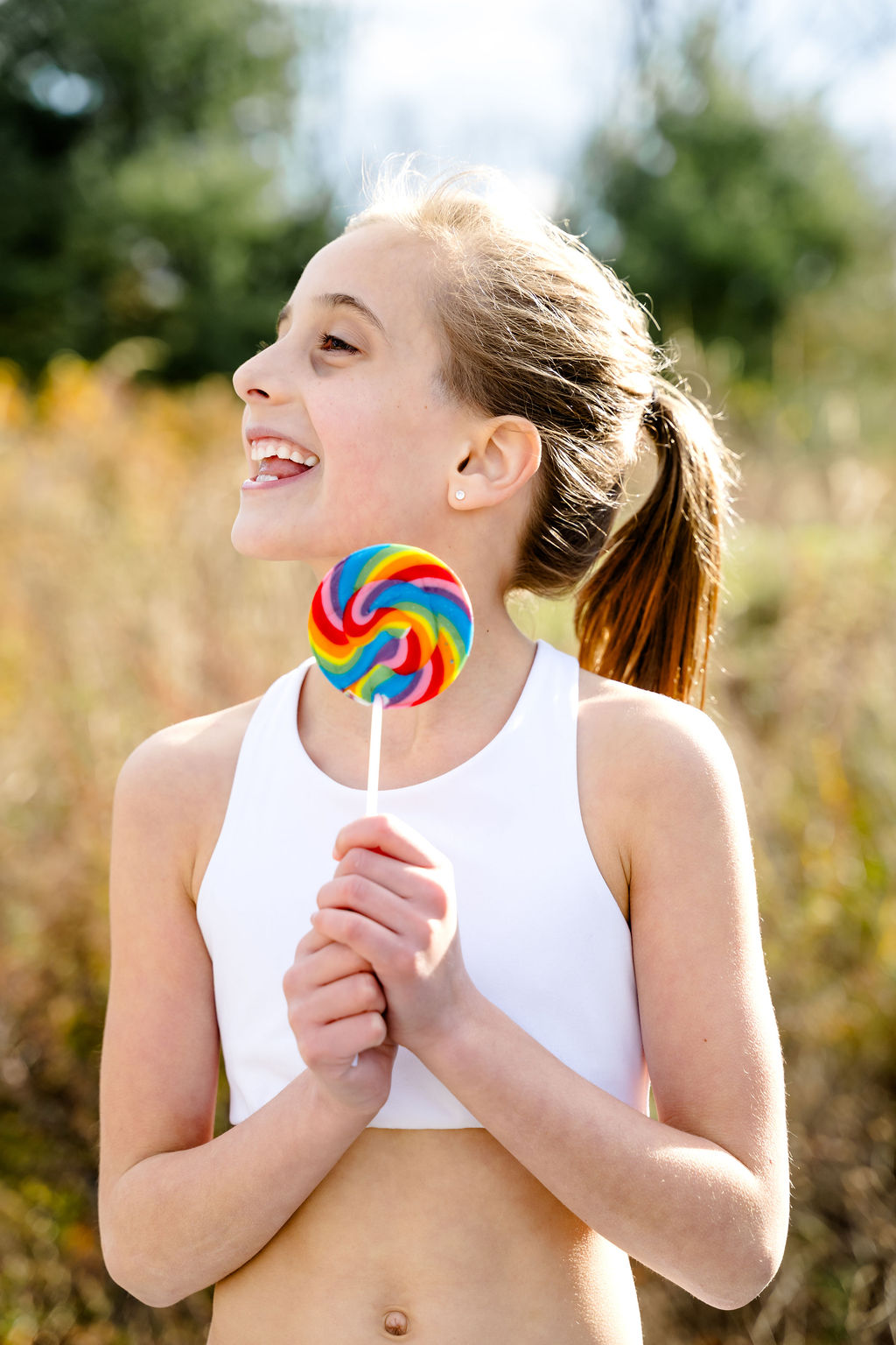 A girl laughing with a rainbow lollipop, from a modeling portfolio shoot