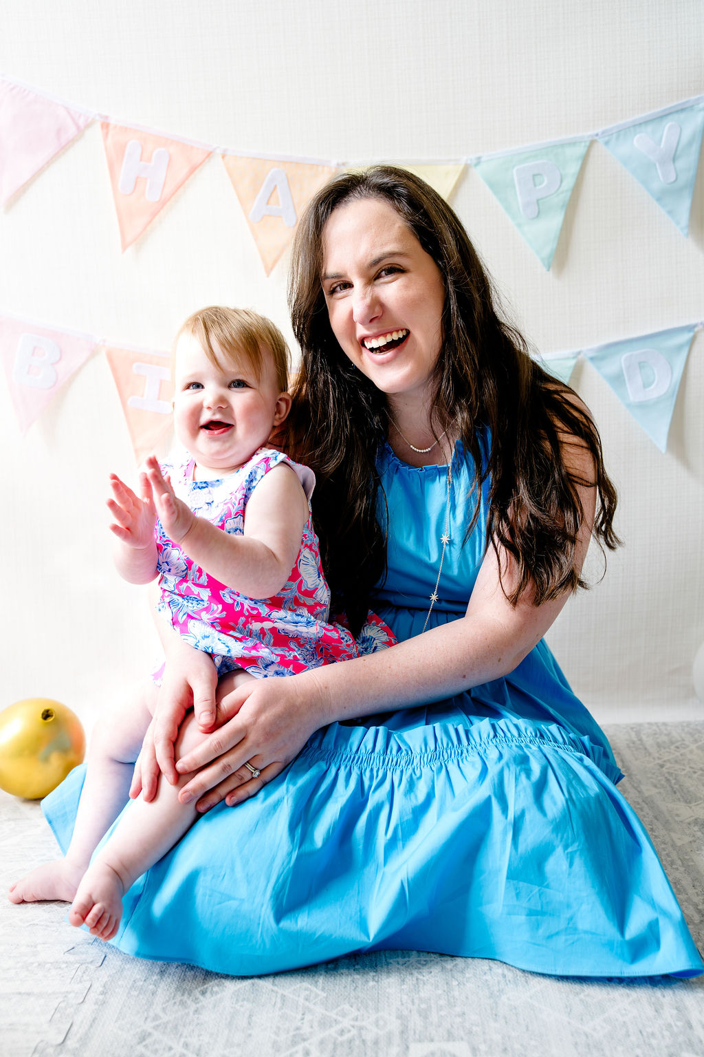 A mother and her baby laughing at a first birthday party