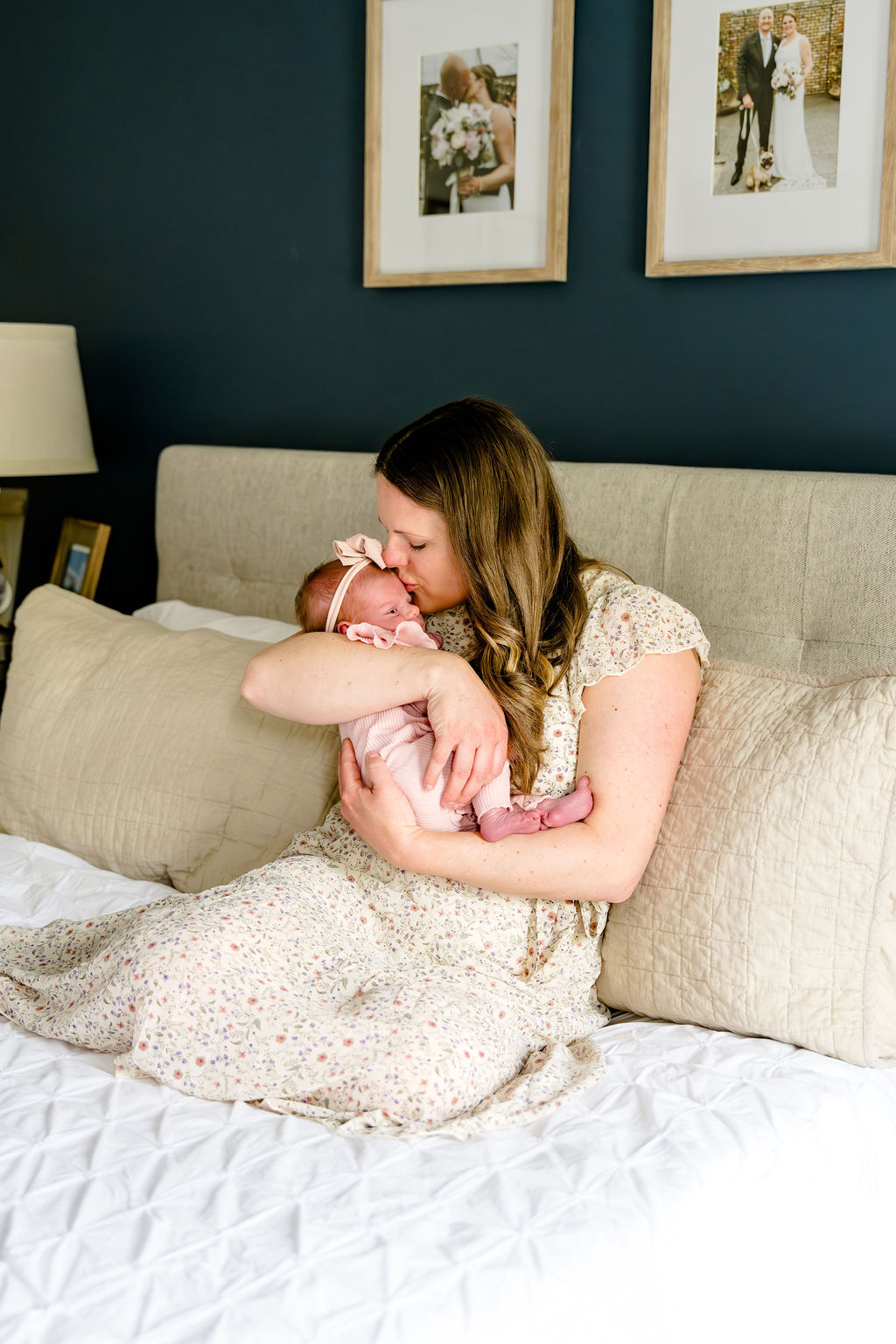 A mother kissing her newborn on the bed at home