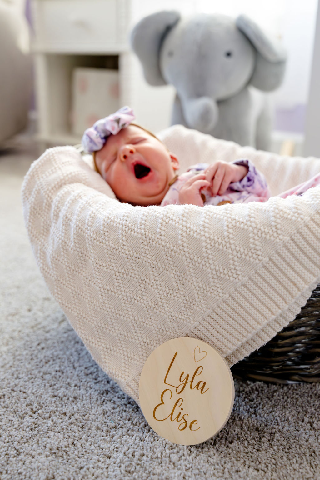 A newborn yawning in a knit-lined basket