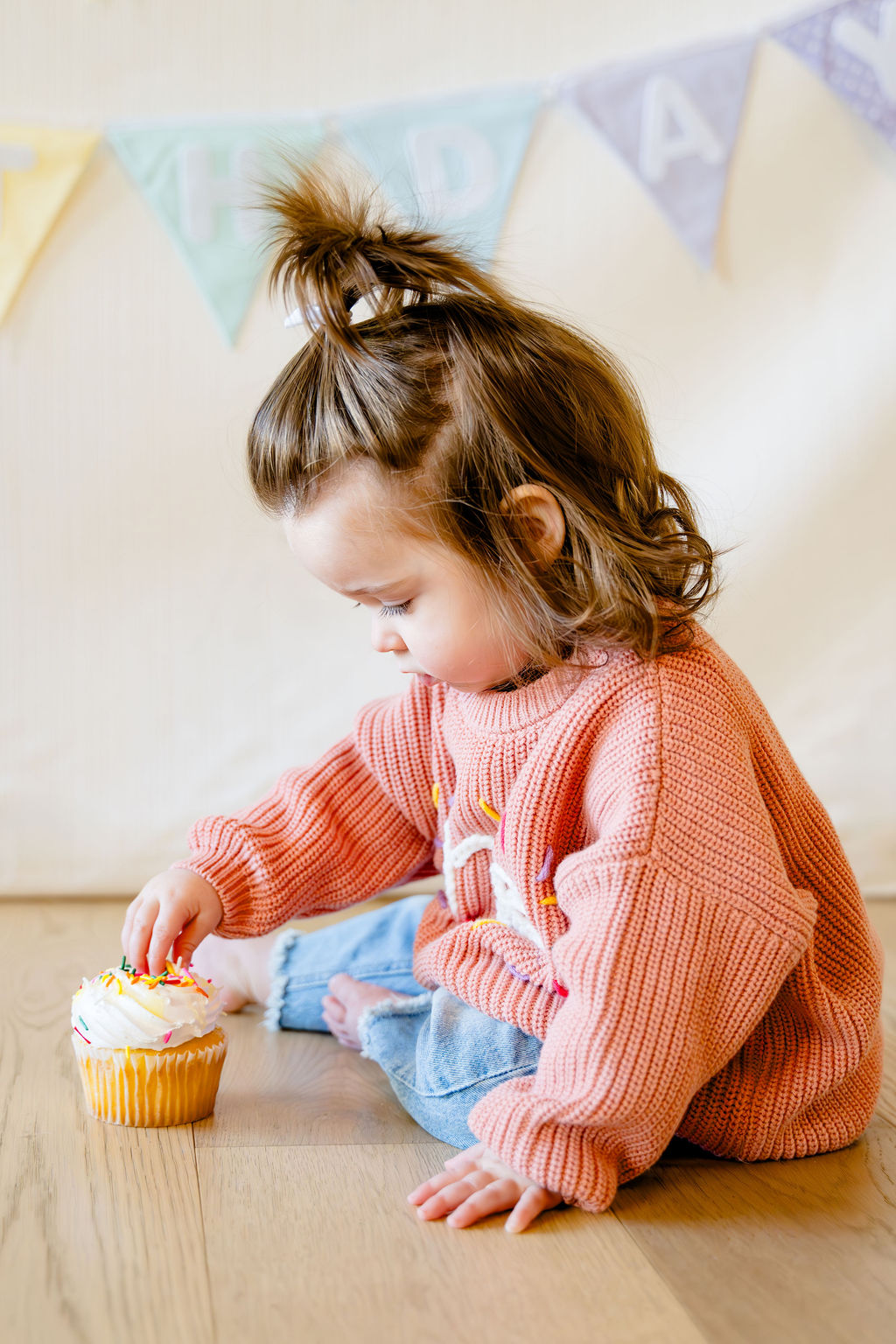 A one-year-old reaching for a birthday cupcake