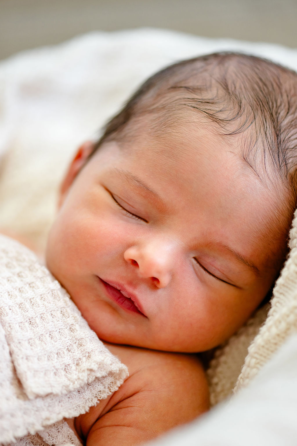 A sleeping newborn resting on a knit blanket