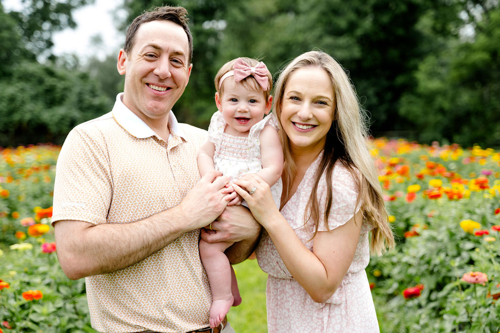 A smiling couple and their baby in a marigold field