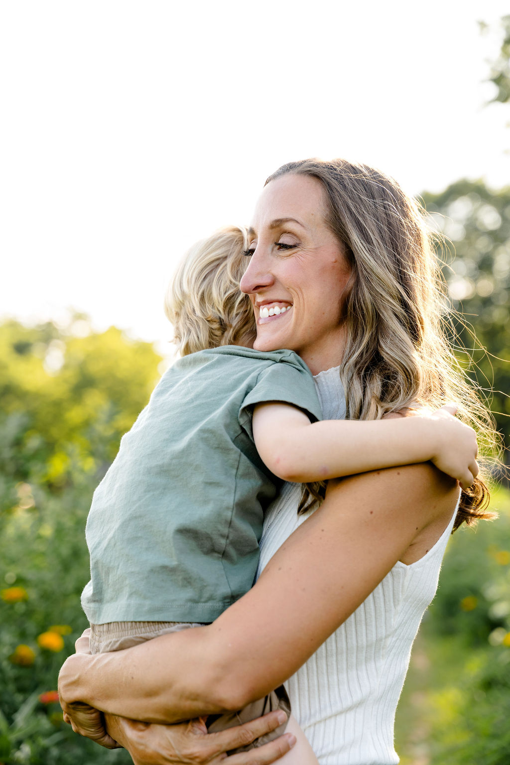 A toddler hugging his mom tight in golden light