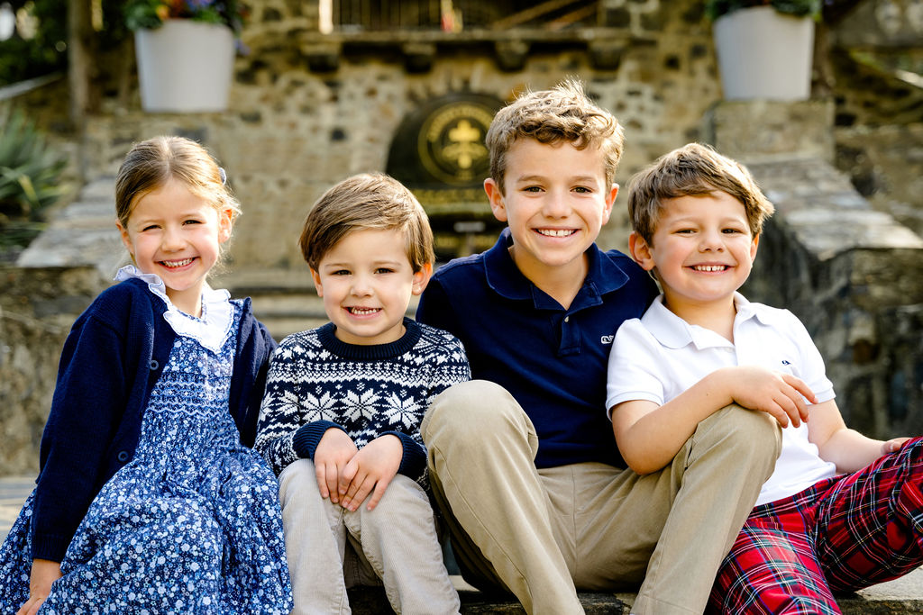 Four siblings in holiday outfits in front of a stone wall
