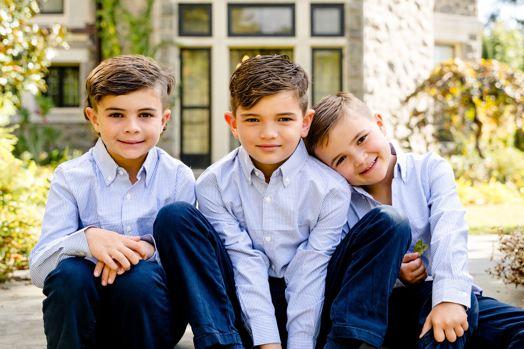 Three brothers sitting together in front of a stone manor