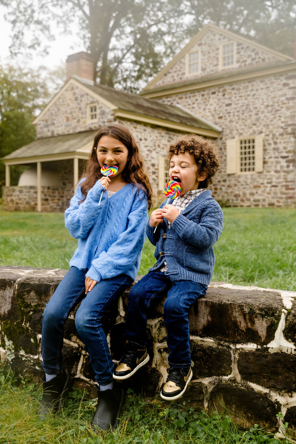 Two brothers with lollipops on a stone wall