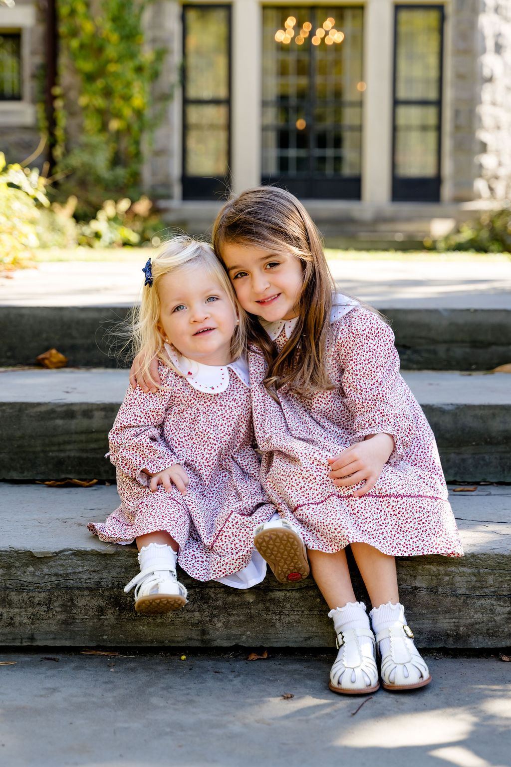 Two sisters in matching dresses on stone steps